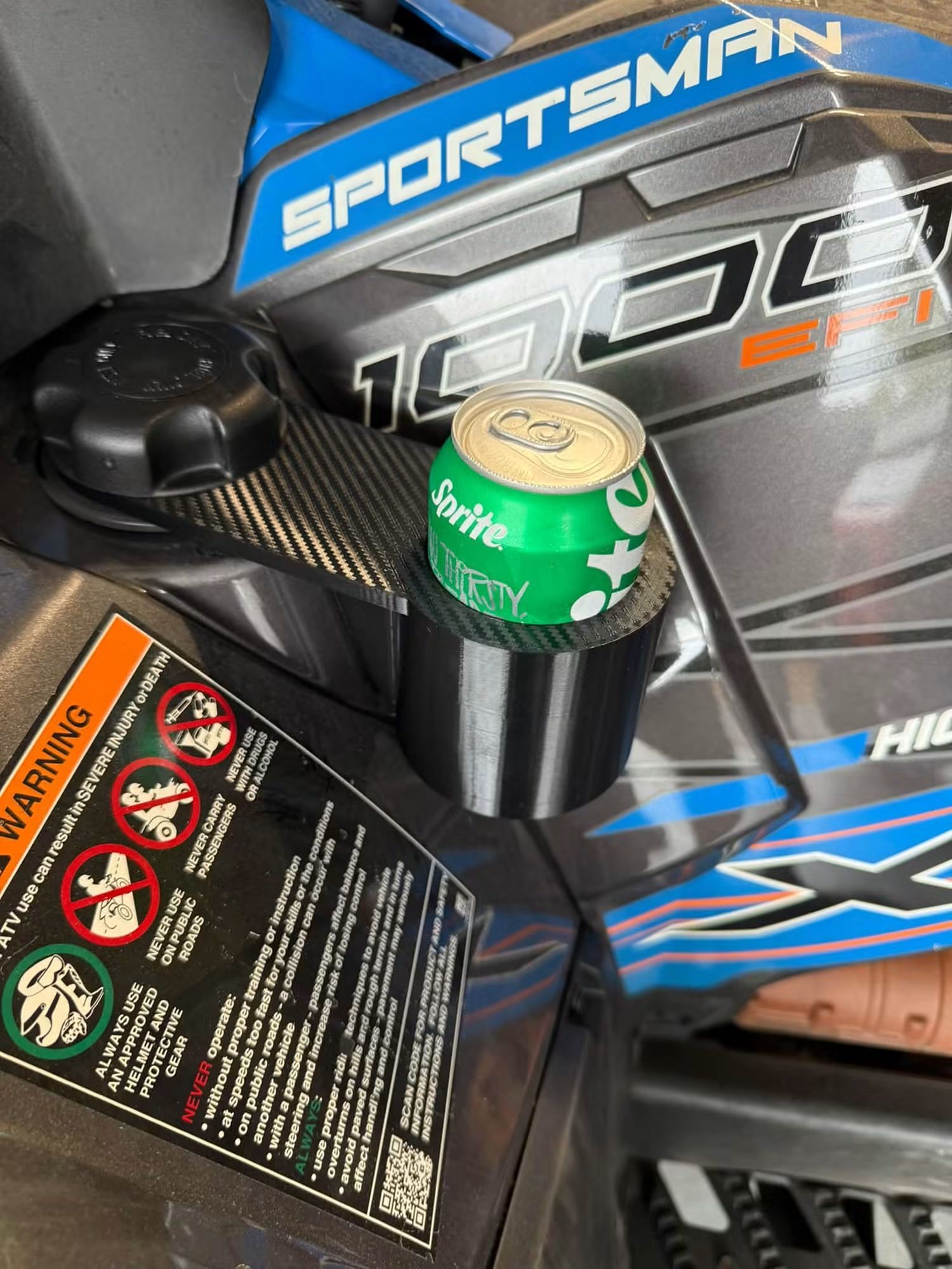 Black Polaris Sportsman 1000 cup holder with a can, mounted on a blue Sportsman 1000